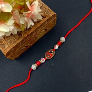 ARNAS 1 PC RED & GOLDEN OM MOTIF CHARMS WITH RED & WHITE PEARL DESIGNER RAKHI